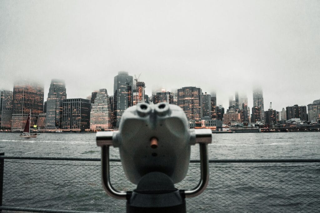 Dramatic view of New York City skyline shrouded in fog from a waterfront viewing deck.