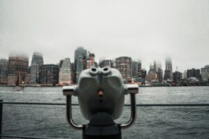 Dramatic view of New York City skyline shrouded in fog from a waterfront viewing deck.