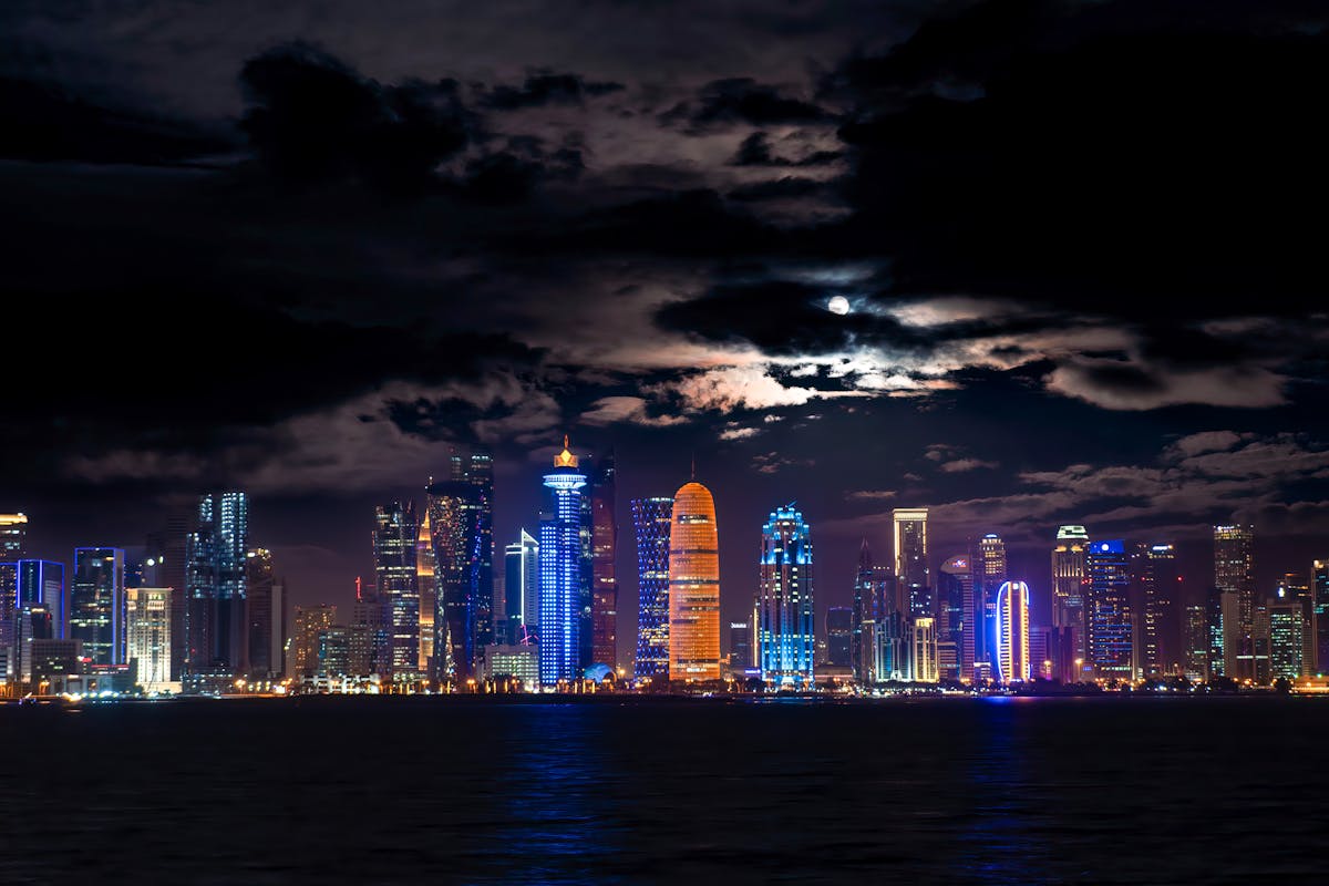 Night panorama of Doha skyline Qatar West Bay towers reflecting on the bay