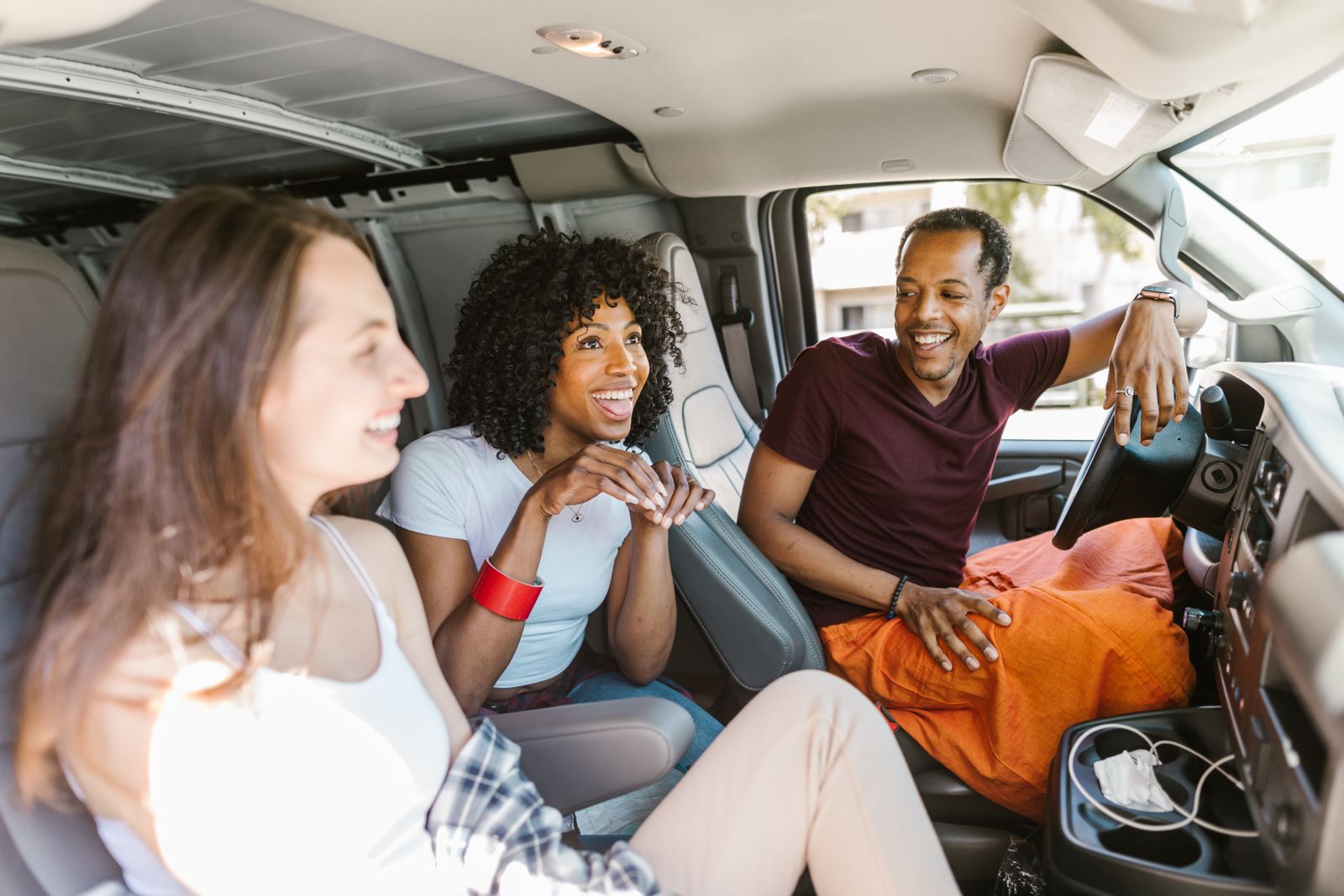 Group of friends laughing together during a road trip in a van