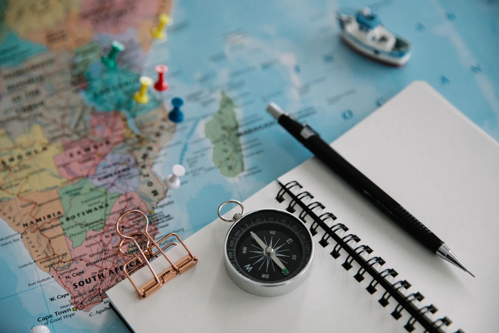 Flat lay of a travel map, compass, notebook and pen for trip planning