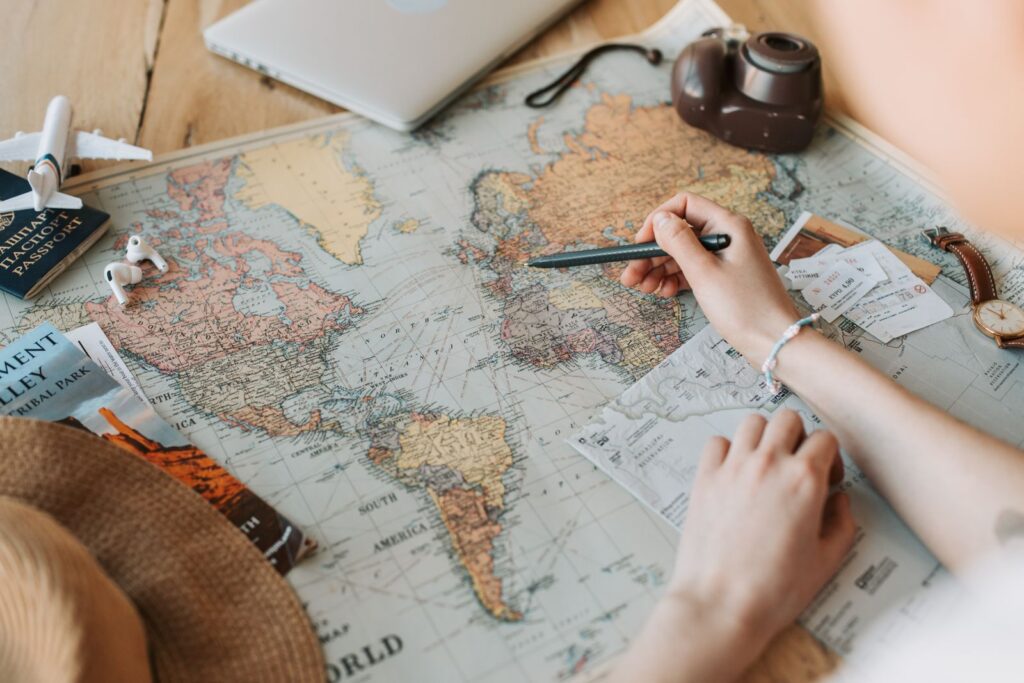Traveler planning a trip on a world map with tickets and camera, the starting point for using the Stamped travel planner app