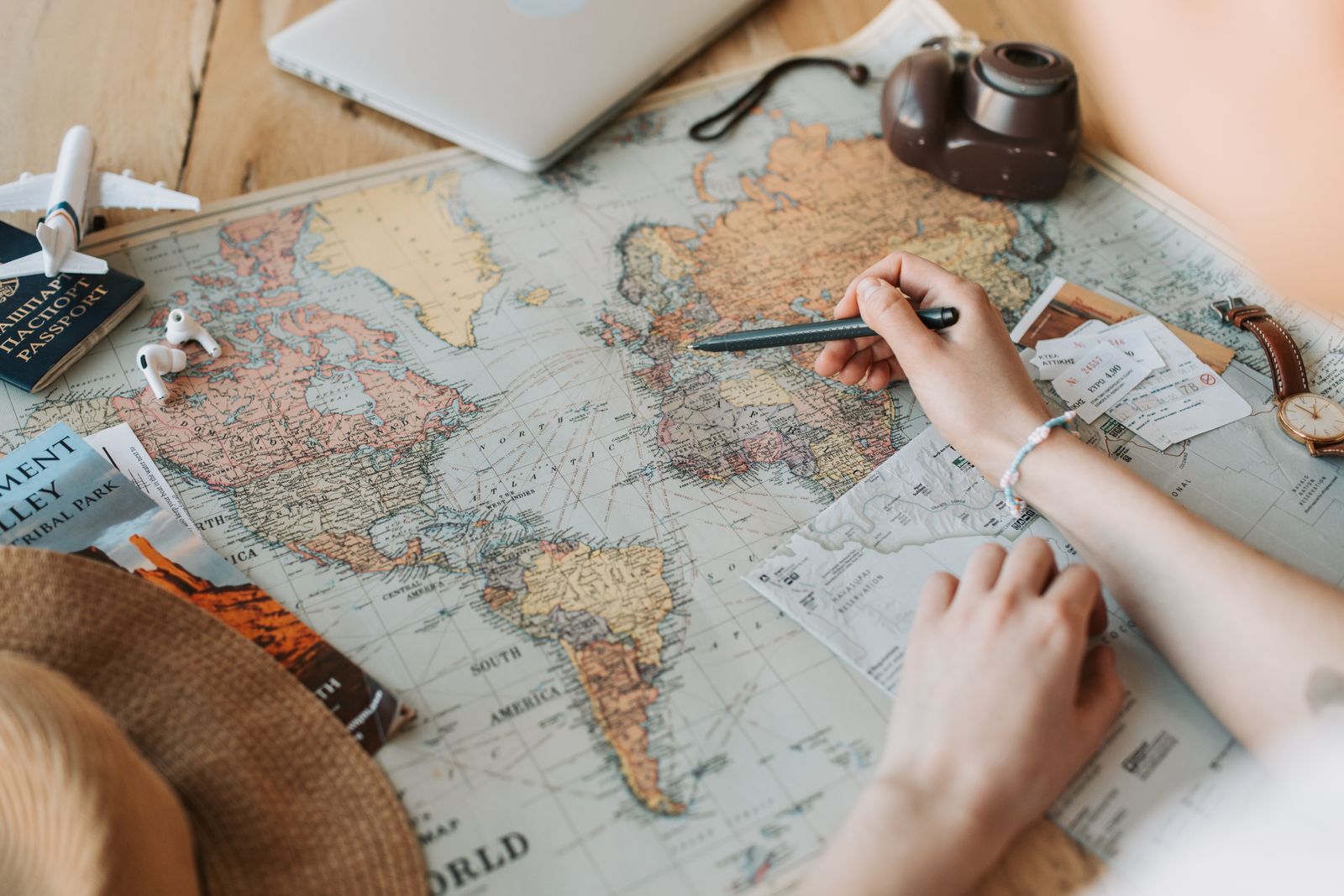 Traveler planning a trip on a world map with tickets and camera, the starting point for using the Stamped travel planner app
