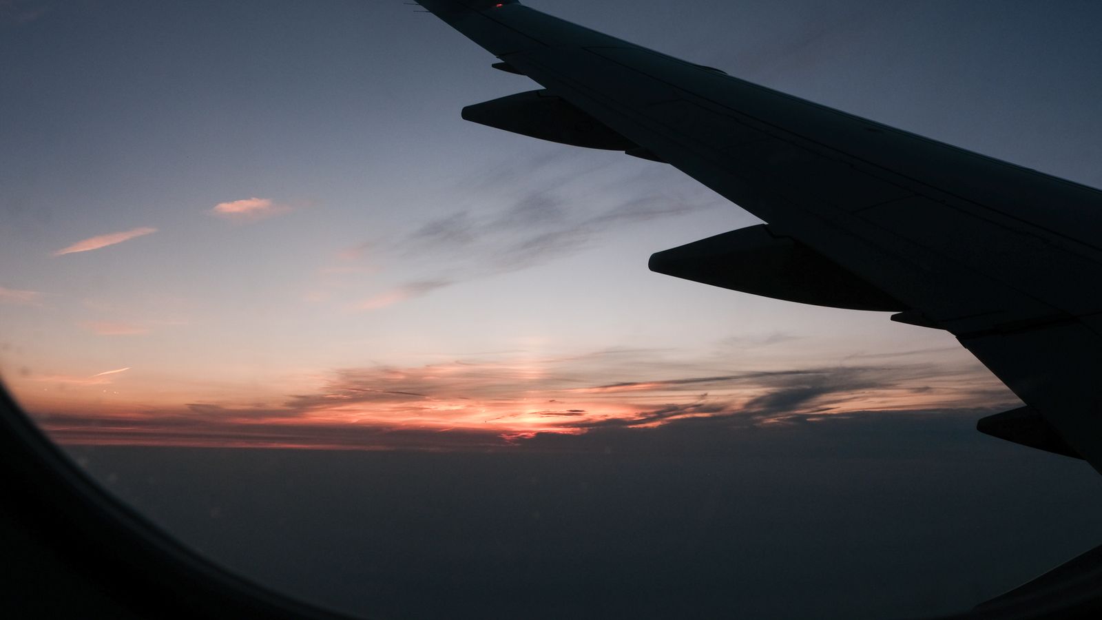 View of an airplane wing above the clouds at sunset on the way to a well planned trip