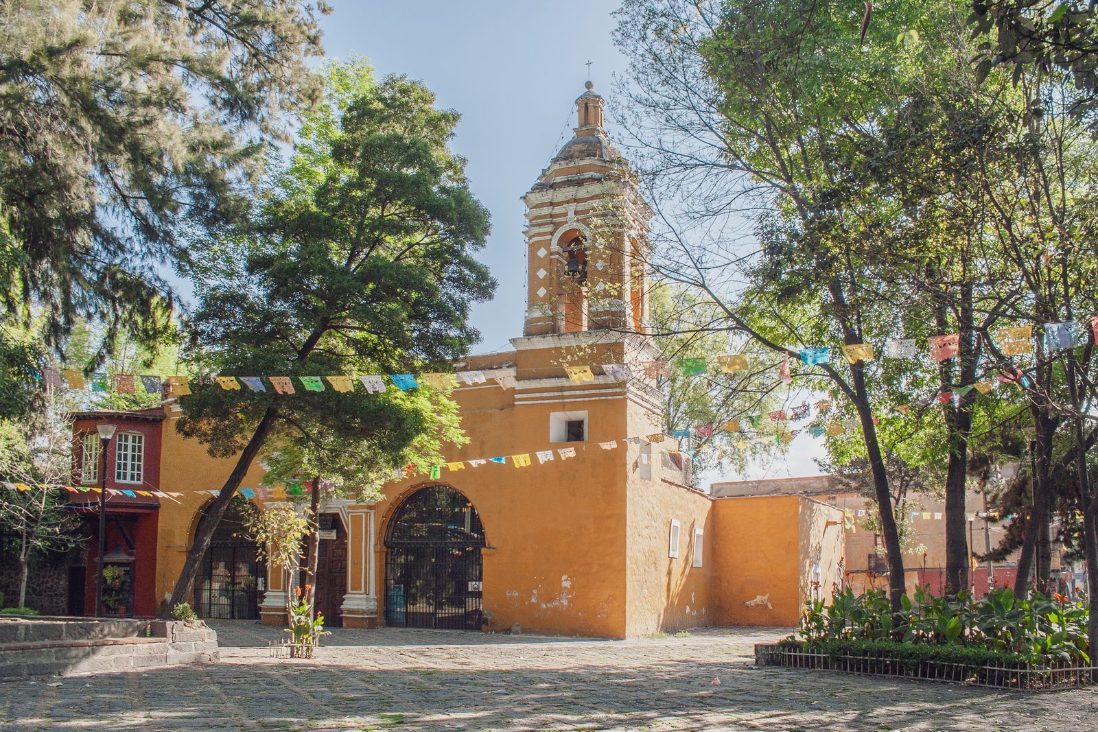 A colonial chapel and cobblestone plaza strung with papel picado in the Coyoacan neighborhood of Mexico City