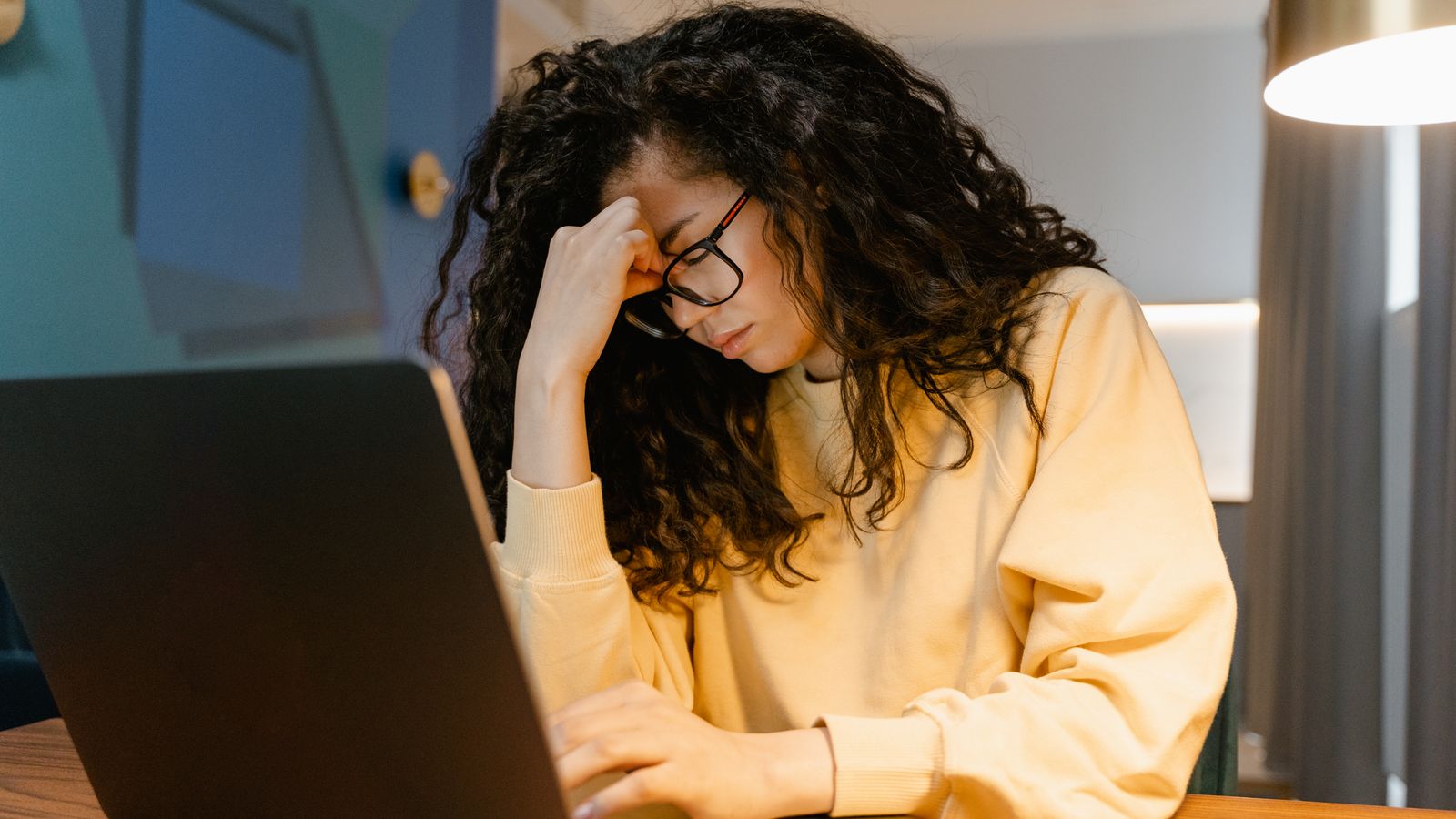 Tired traveler with glasses showing decision fatigue while planning a vacation at a desk