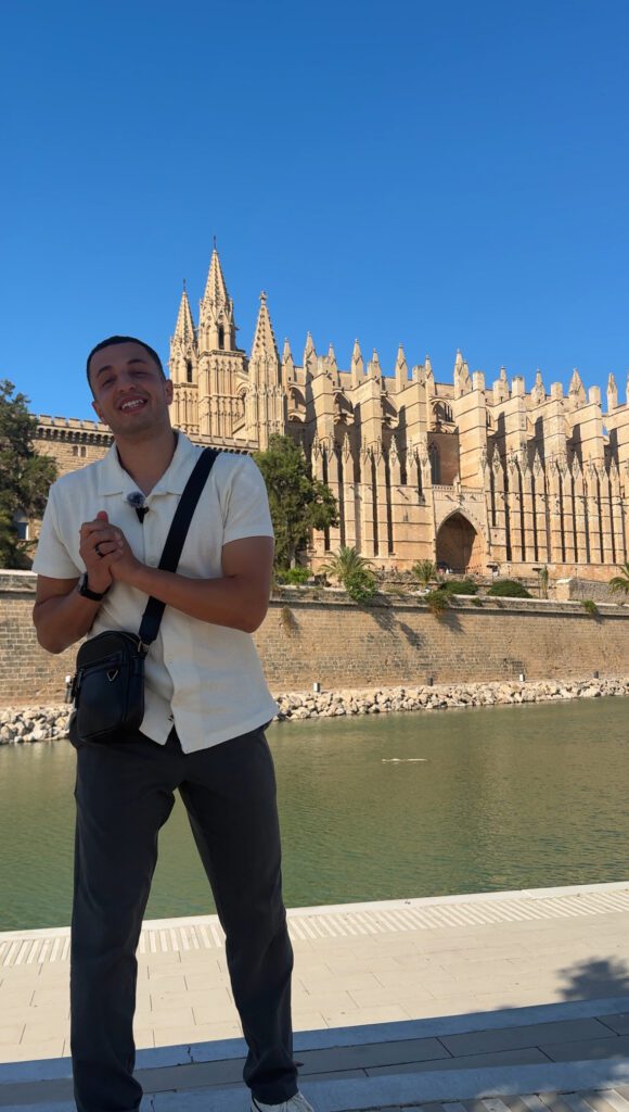 Ryan in front of a gothic cathedral by the water