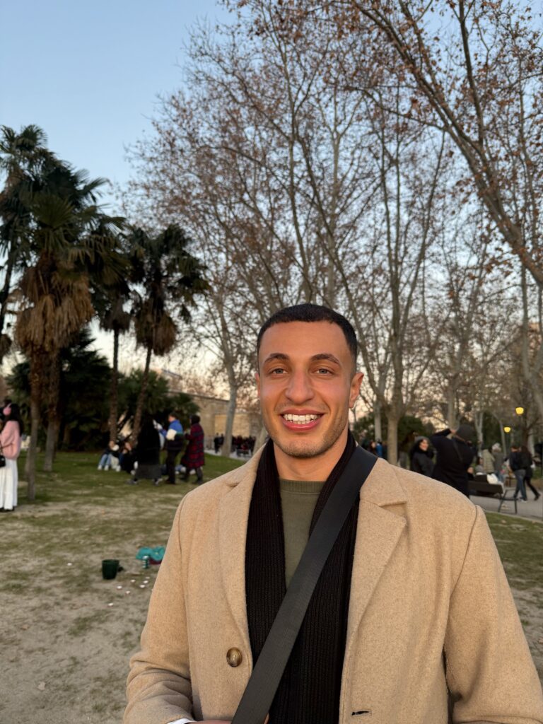 Ryan, founder of The Next Stamp Travel Co., smiling in a park at golden hour