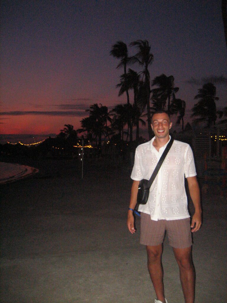 Ryan on a beach at sunset with palm trees
