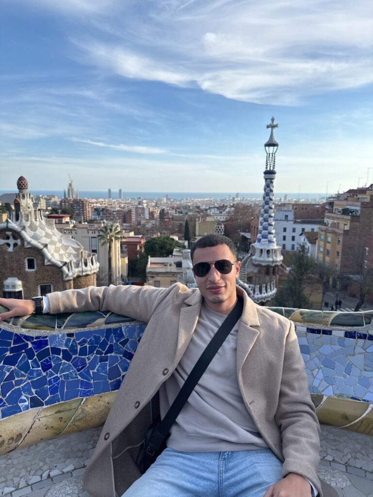 Ryan seated beside the mosaic terrace at Park Güell in Barcelona