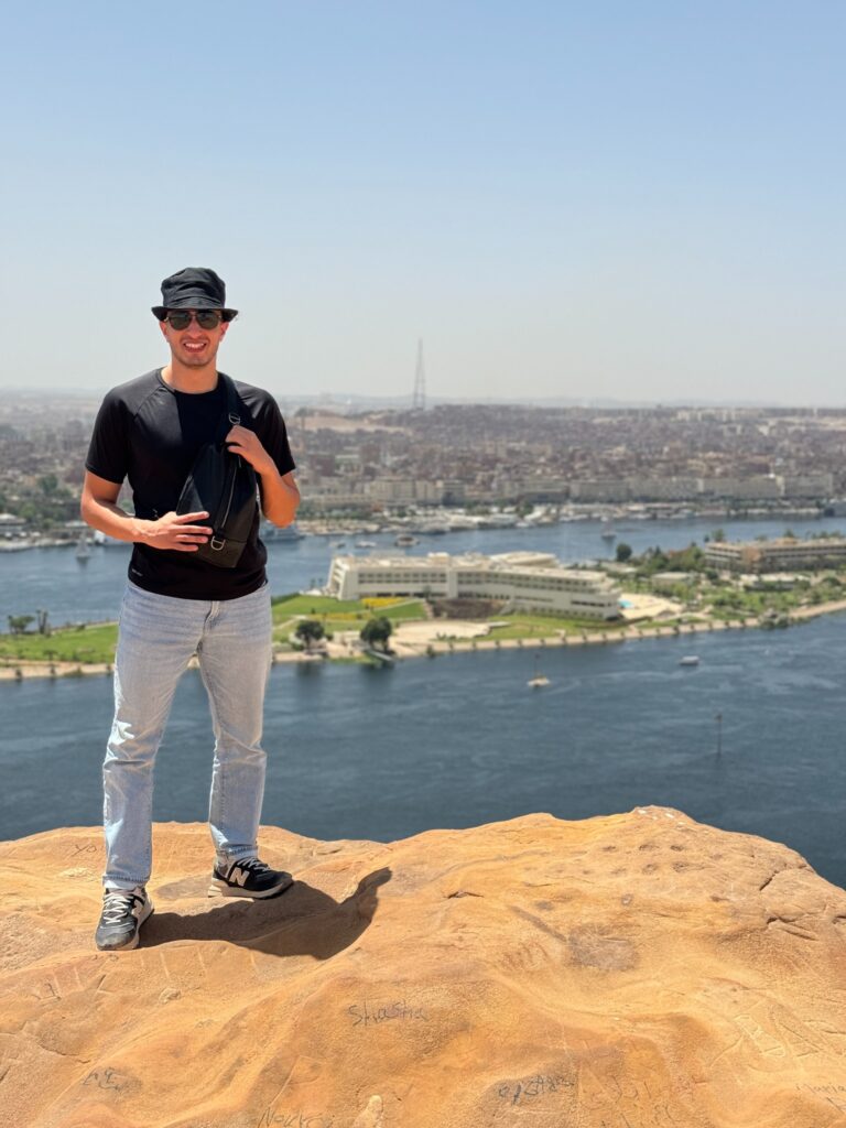 Ryan overlooking a river and city from a rocky viewpoint