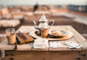 A warm scene of Moroccan tea and cards on a rooftop wooden table in Marrakesh.